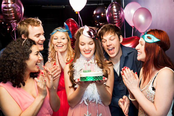 Woman holding birthday cake with friends around